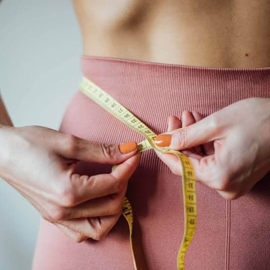 Mulher medindo a cintura com uma fita métrica